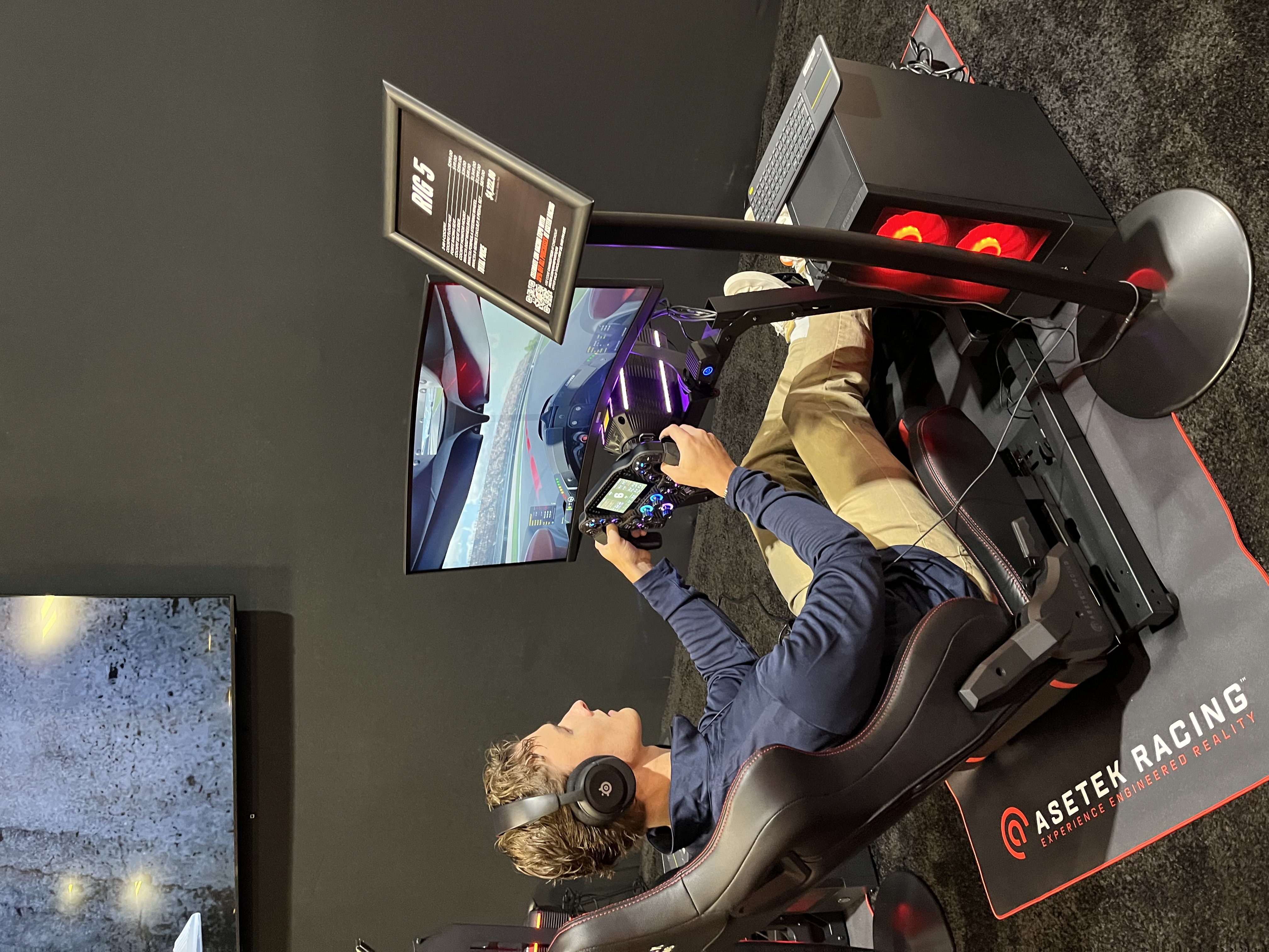 Ian Strohmen on the big screen during a Sim Racing Expo panel, wearing a Ready Set Sim shirt